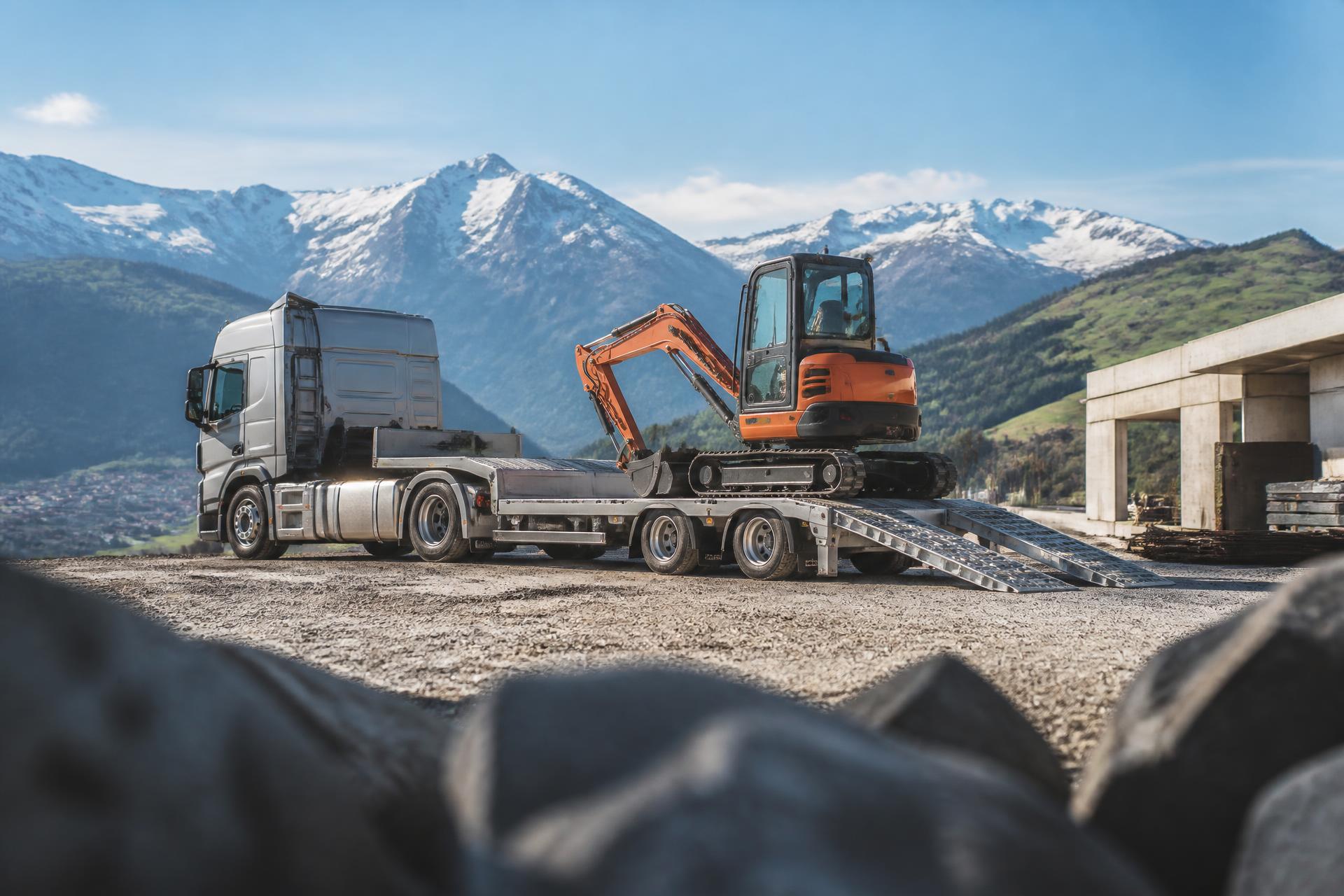 Tieflader verlädt einen Minibagger auf einer Schweizer Baustelle
